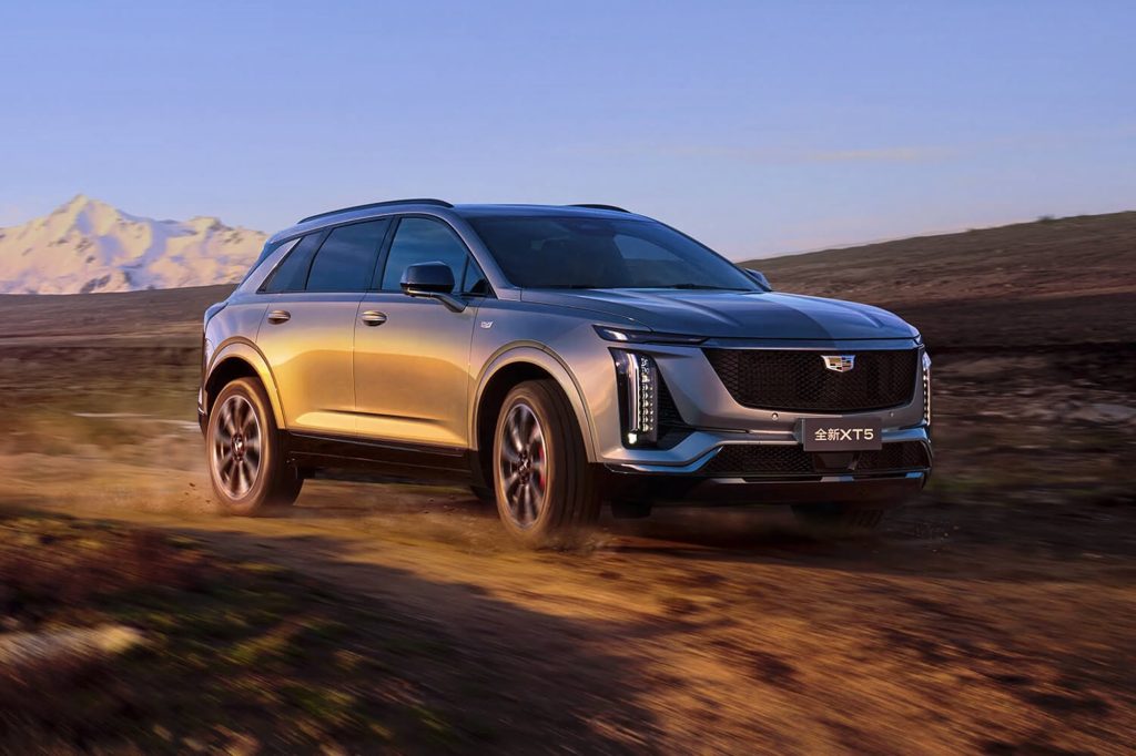 2025-Cadillac-XT5-China-Press-Photos-Exterior-005-side-front-three-quarters | Wagner Certified Collision Silver Cadillac SUV driving on a dusty desert road with distant mountains at sunset.