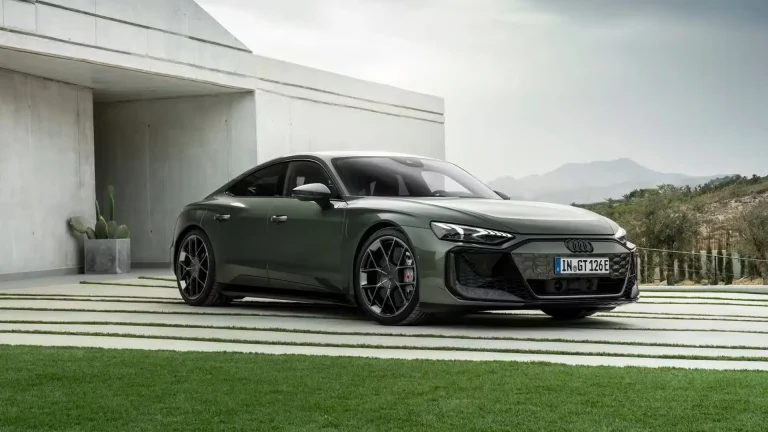 Green Audi sports sedan parked beside a modern concrete building with desert landscape in the background.