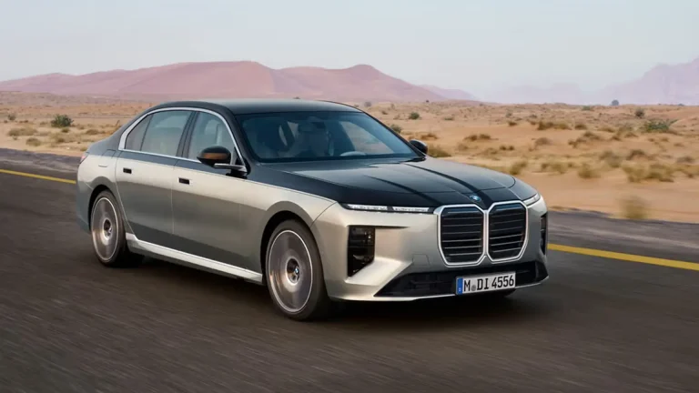 Silver BMW sedan driving on a desert highway with distant pink mountains and sparse vegetation in the background